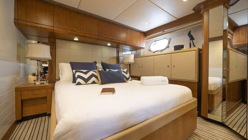 a bed with a white sheet and pillows in a room with wood cabinets aboard PIPELINER Yacht for Sale