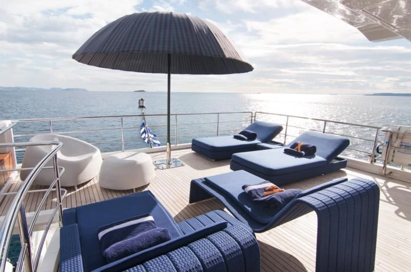 a lounge chair and umbrella on a deck overlooking the ocean aboard MEMORIES TOO Yacht for Sale