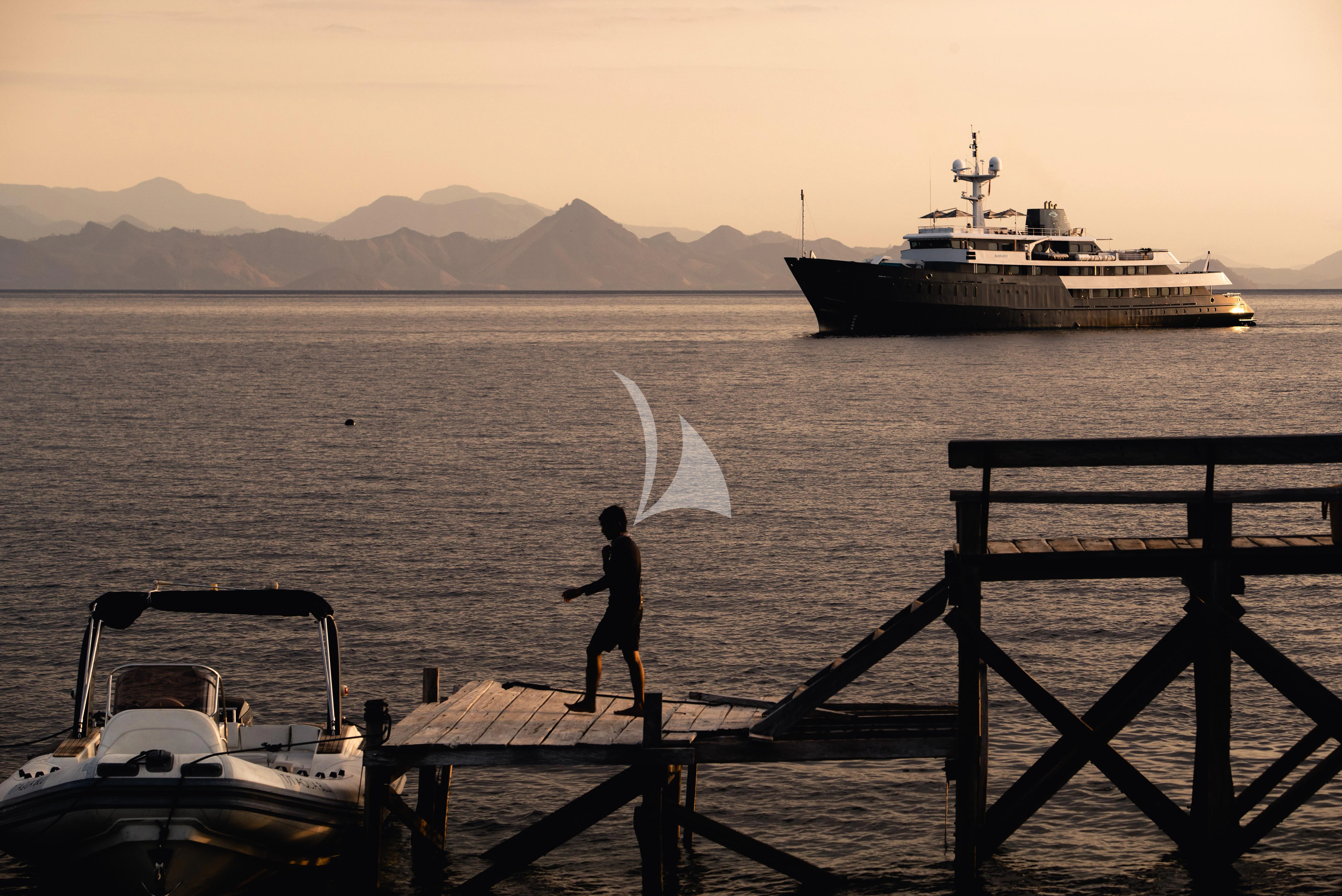 a person standing on a dock next to a boat in the water aboard AQUA BLU Yacht for Sale