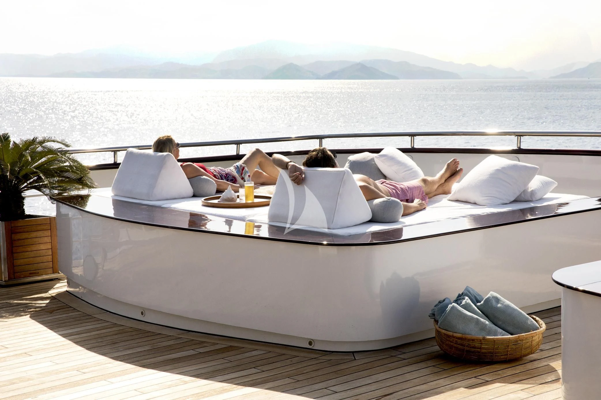 a couple of people lying on a couch on a deck with a large body of water in the aboard AQUA BLU Yacht for Sale