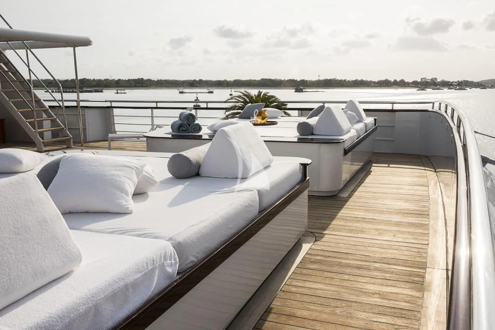 a balcony with a large bed and a table with chairs on it aboard AQUA BLU Yacht for Sale