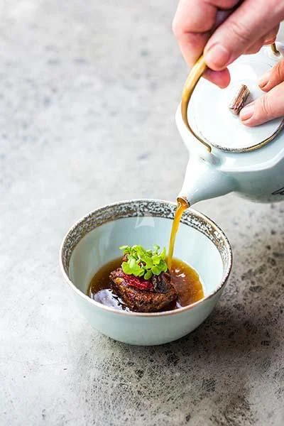 a hand pouring a substance into a white cup aboard AQUA BLU Yacht for Sale