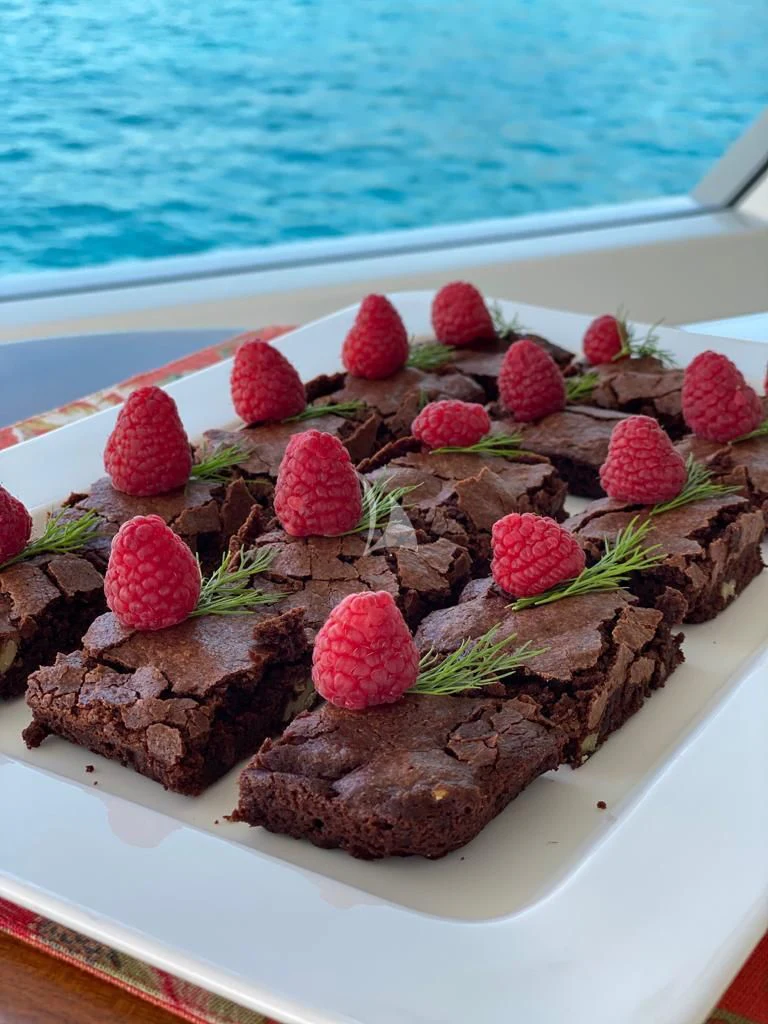 a pile of red berries on a white plate next to a body of water aboard R23 Yacht for Charter