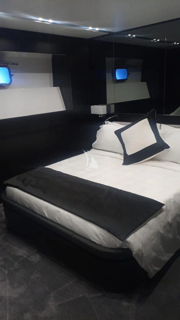 a bed with a black and white bed spread and a blue screen aboard R23 Yacht for Charter