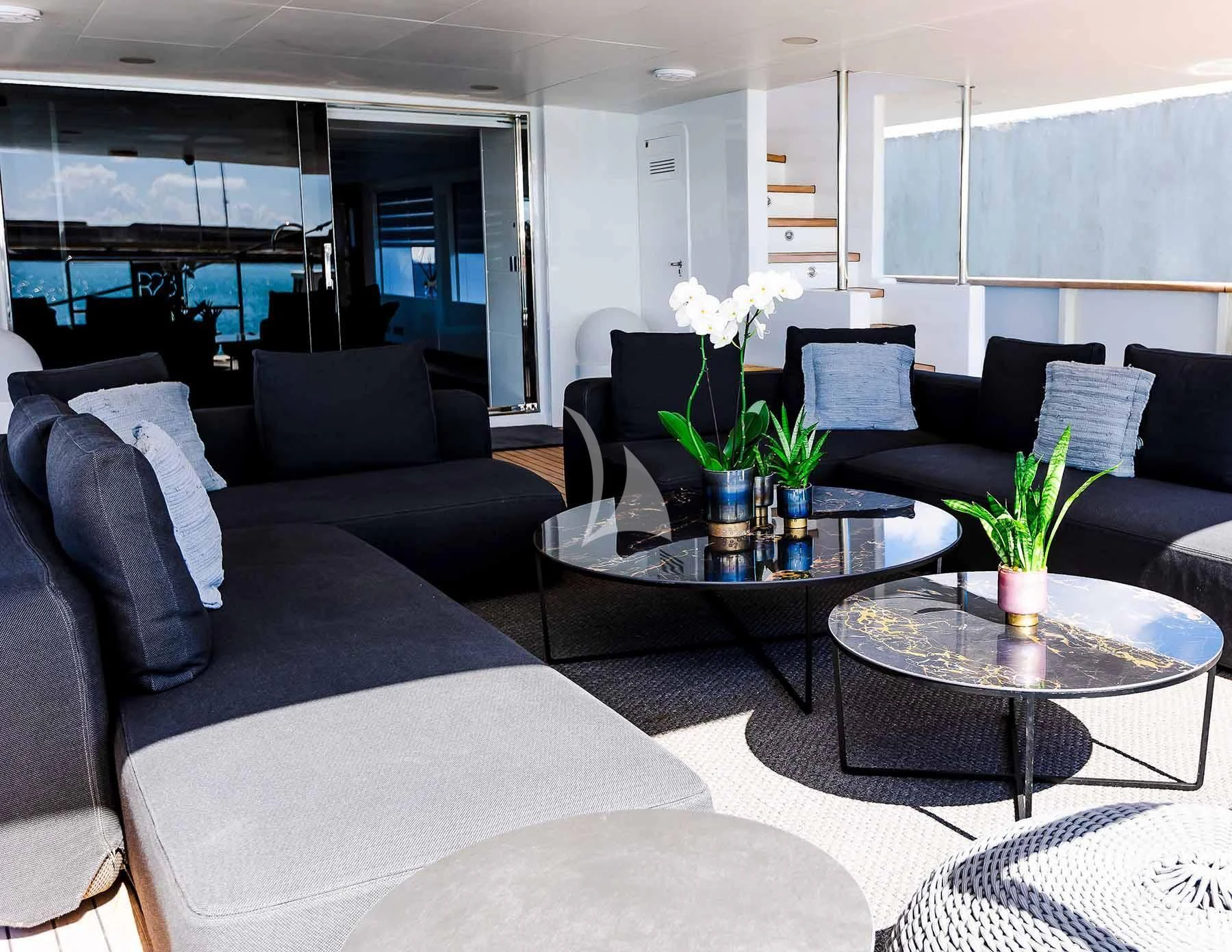 a living room with black couches and white pillows aboard R23 Yacht for Charter