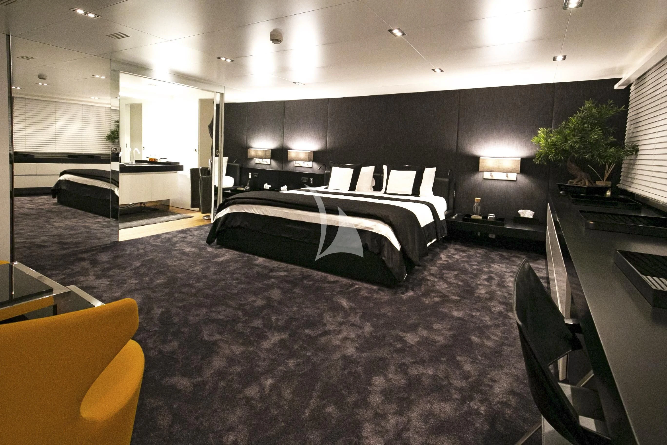 a large room with a bed and desks aboard R23 Yacht for Charter