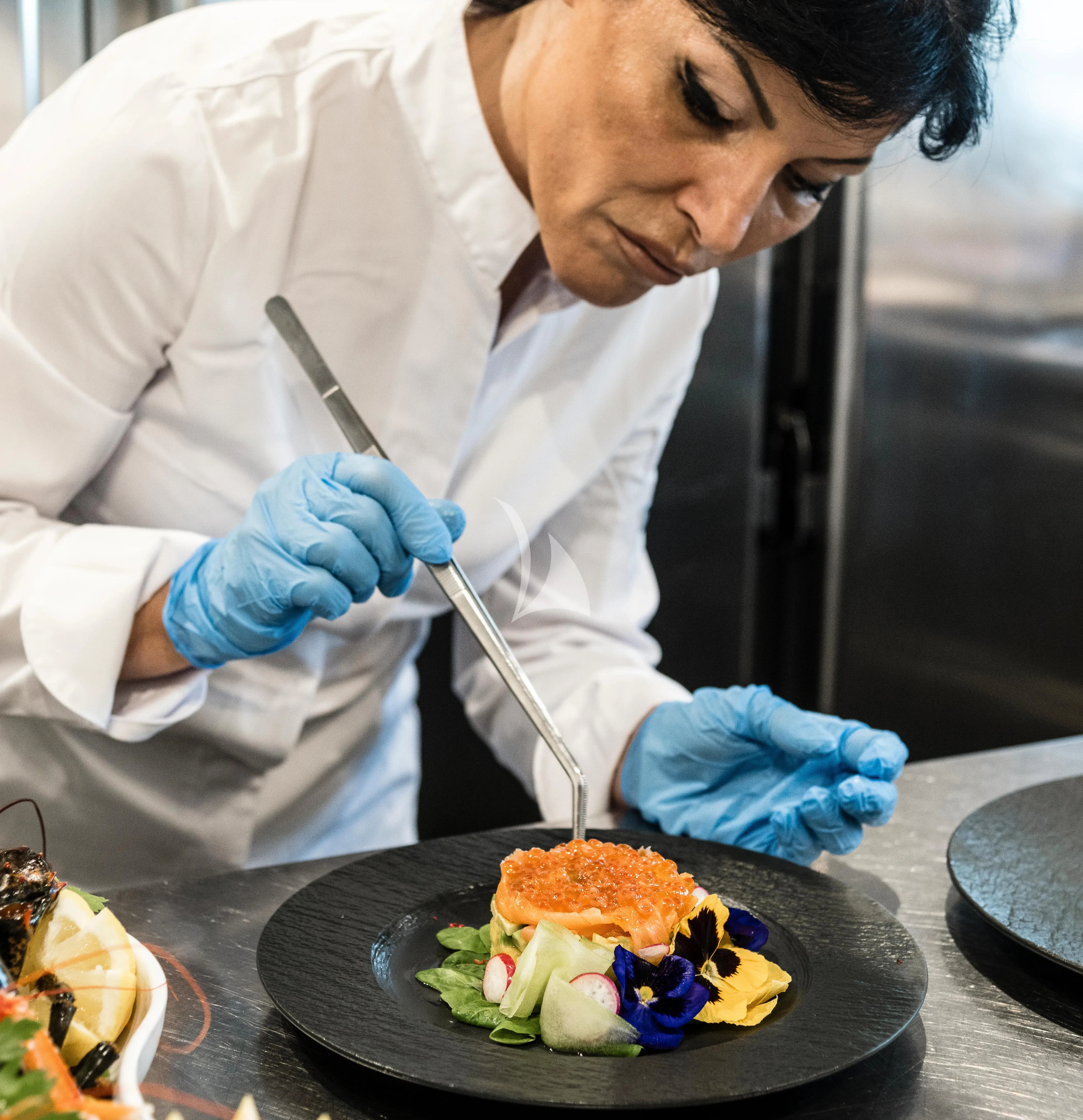 a man wearing gloves and a white coat is preparing food aboard R23 Yacht for Charter