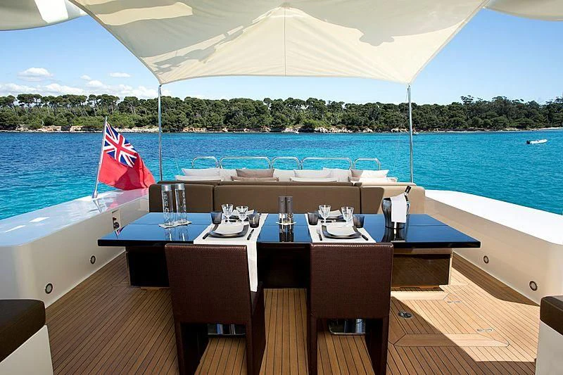 a table set for a meal on a deck overlooking a large body of water aboard ALEON Yacht for Sale