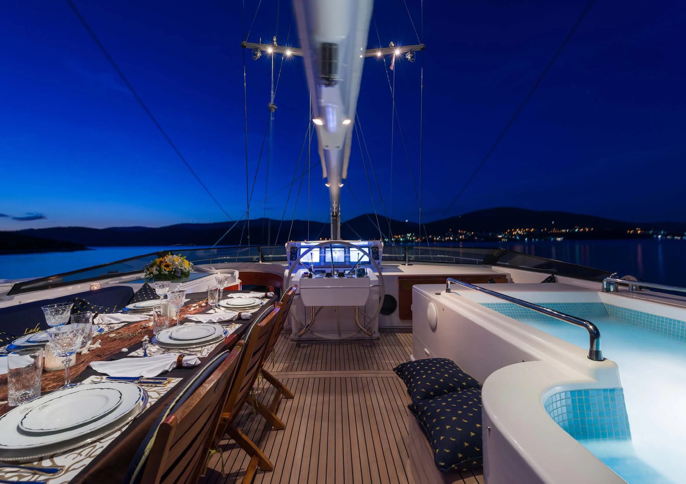 a deck with a table and chairs on it and a boat on the water in the background aboard LADY SUNSHINE Yacht for Sale