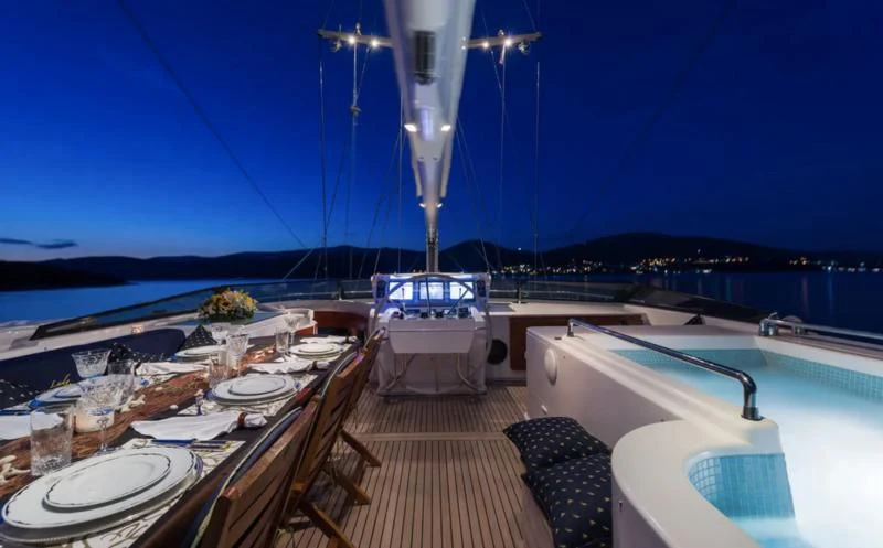 a deck with a table and chairs on it and a view of the water and a city in aboard LADY SUNSHINE Yacht for Sale