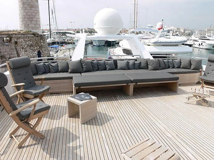 a deck with a table and chairs on it and boats in the background aboard LADY IN BLUE Yacht for Sale