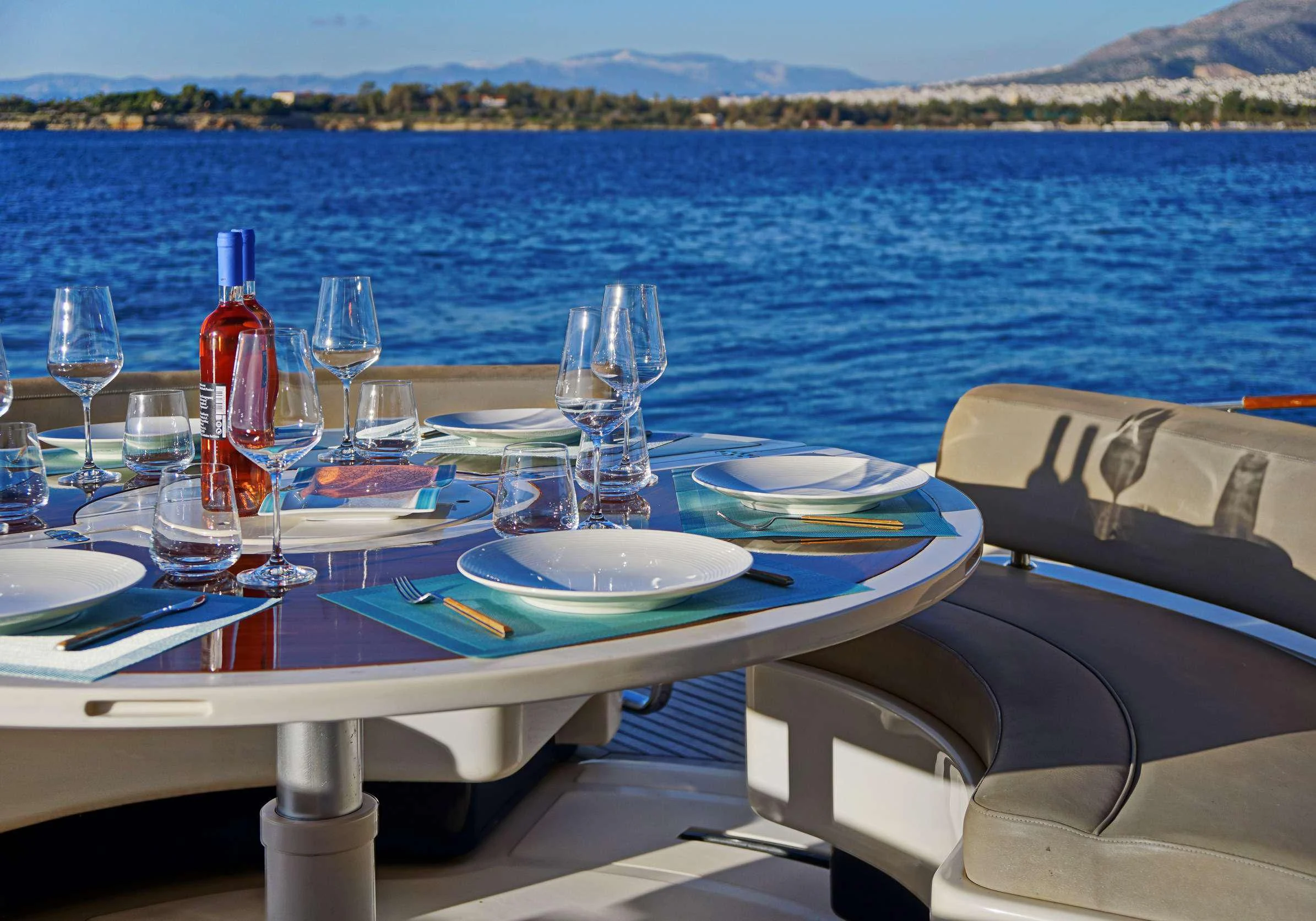 a table with plates and glasses on it by a body of water aboard SEA U Yacht for Charter
