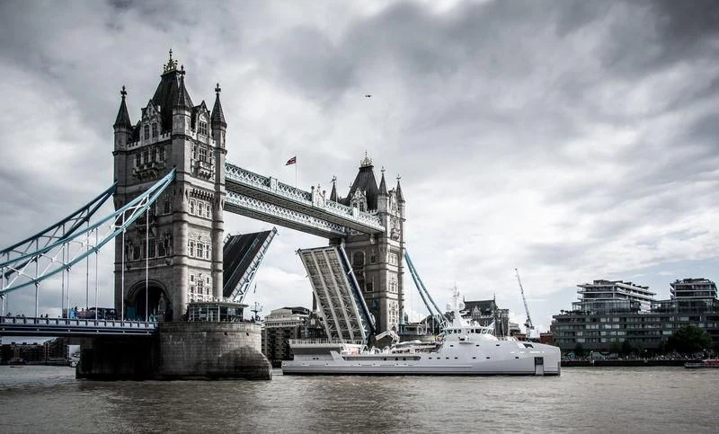 a large bridge over a body of water with a boat in front of it with Tower Bridge in the background aboard GAME CHANGER Yacht for Sale
