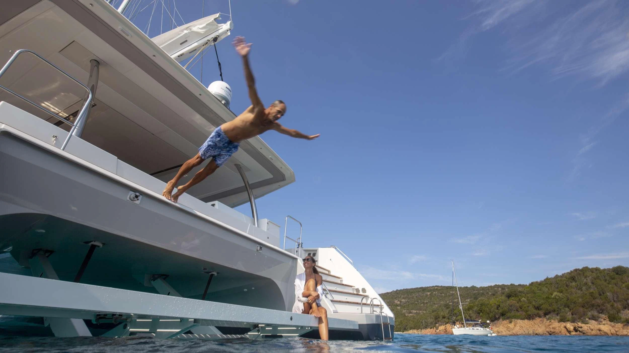 a man and woman jumping off a boat aboard KIMATA Yacht for Charter