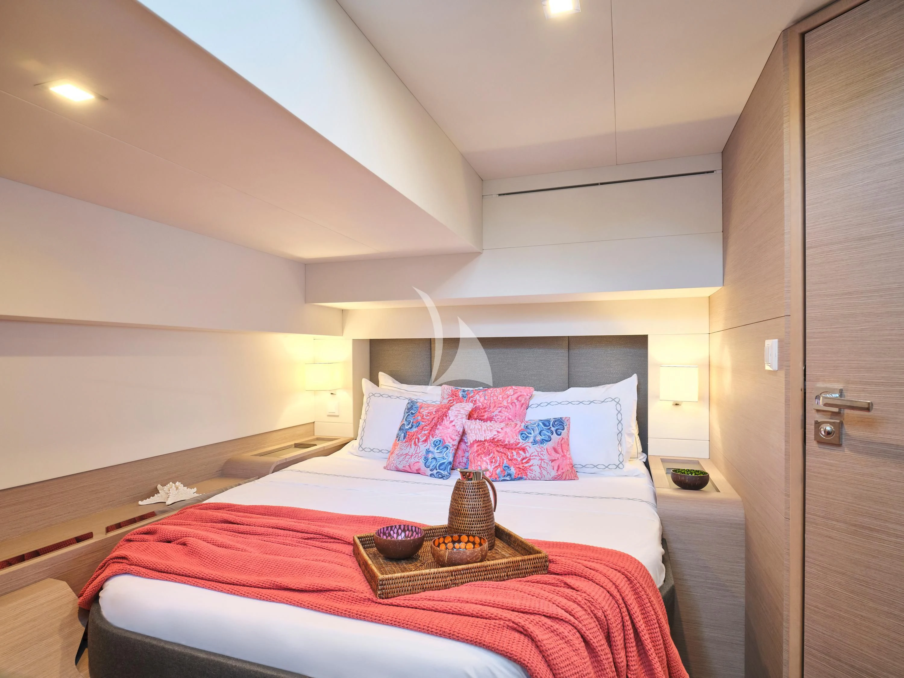 a bed with a red and white bed spread and a brown pillow on a white bed with a aboard KIMATA Yacht for Charter