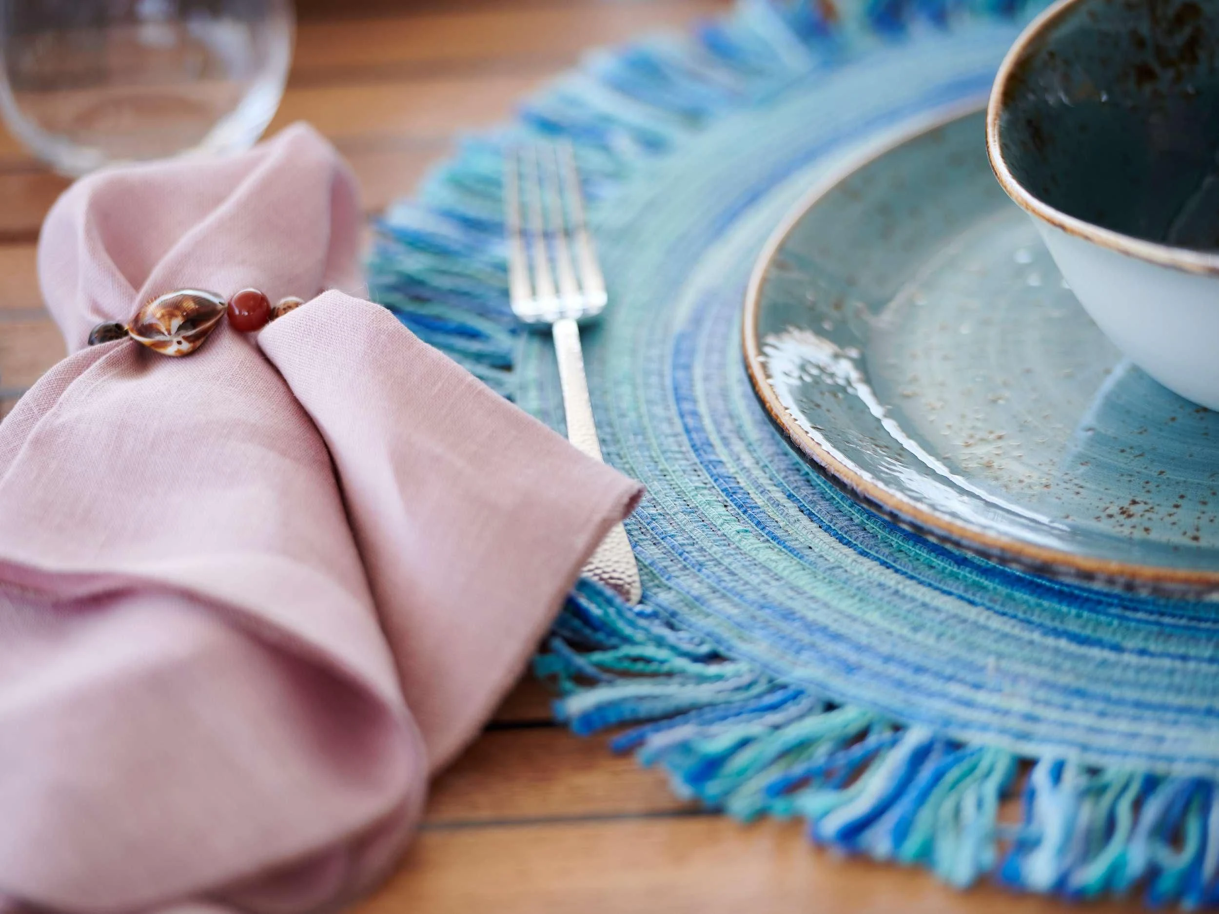 a hand holding a pink glove next to a plate with a fork aboard KIMATA Yacht for Charter