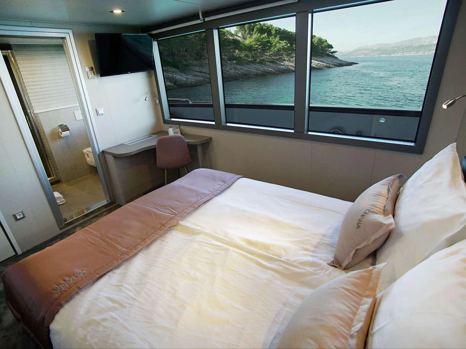 a bed with a large window aboard OHANA Yacht for Sale