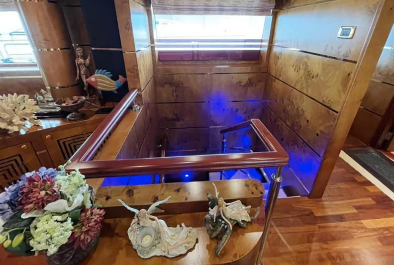 a room with wooden floors and a wood bench with flowers on it aboard NASAYEM Yacht for Sale
