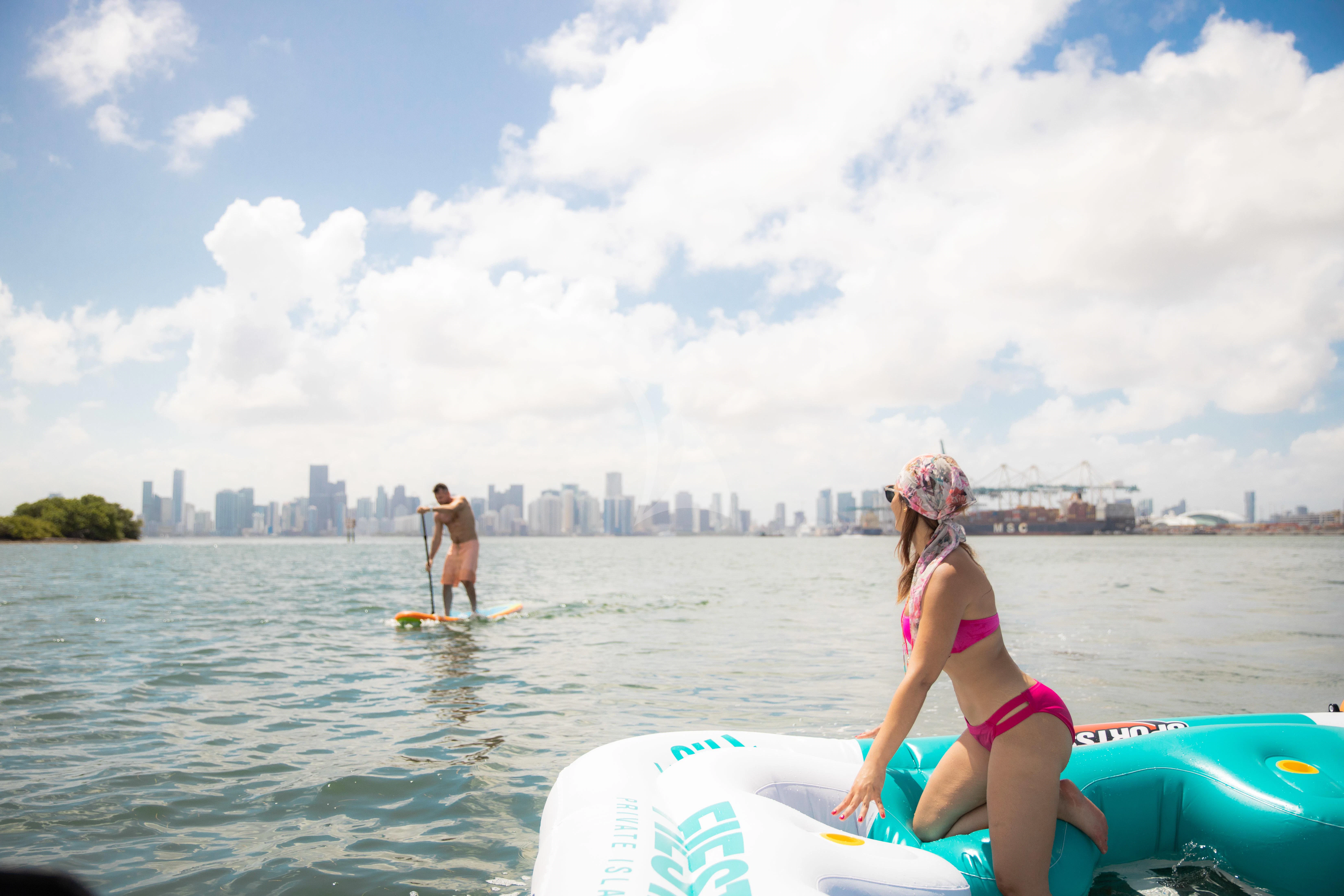 a woman in a bikini on a surfboard in the water aboard M Yacht for Charter