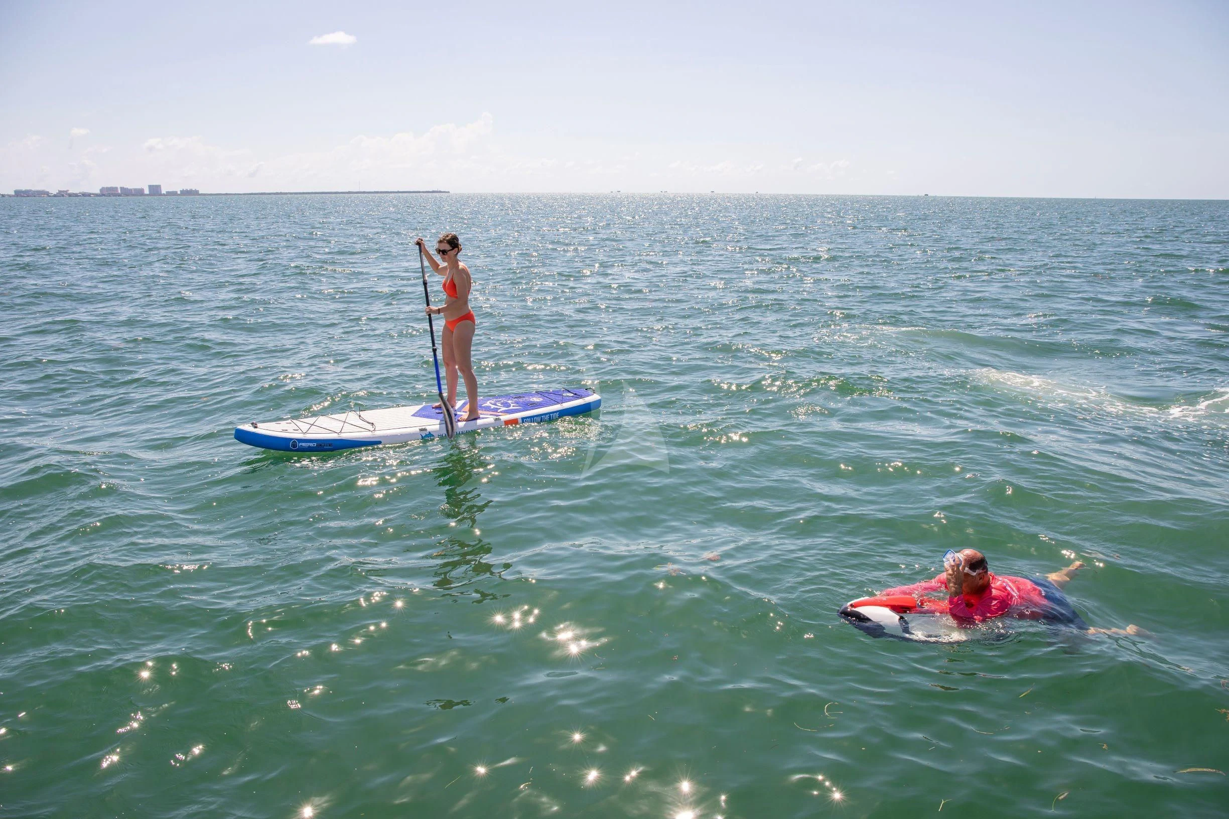 a man standing on a surfboard with a paddle and a woman on a surfboard in the aboard JUST ONE MORE Yacht for Sale