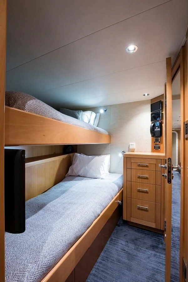 a bed with a desk and a television in a room aboard SERENITY Yacht for Sale