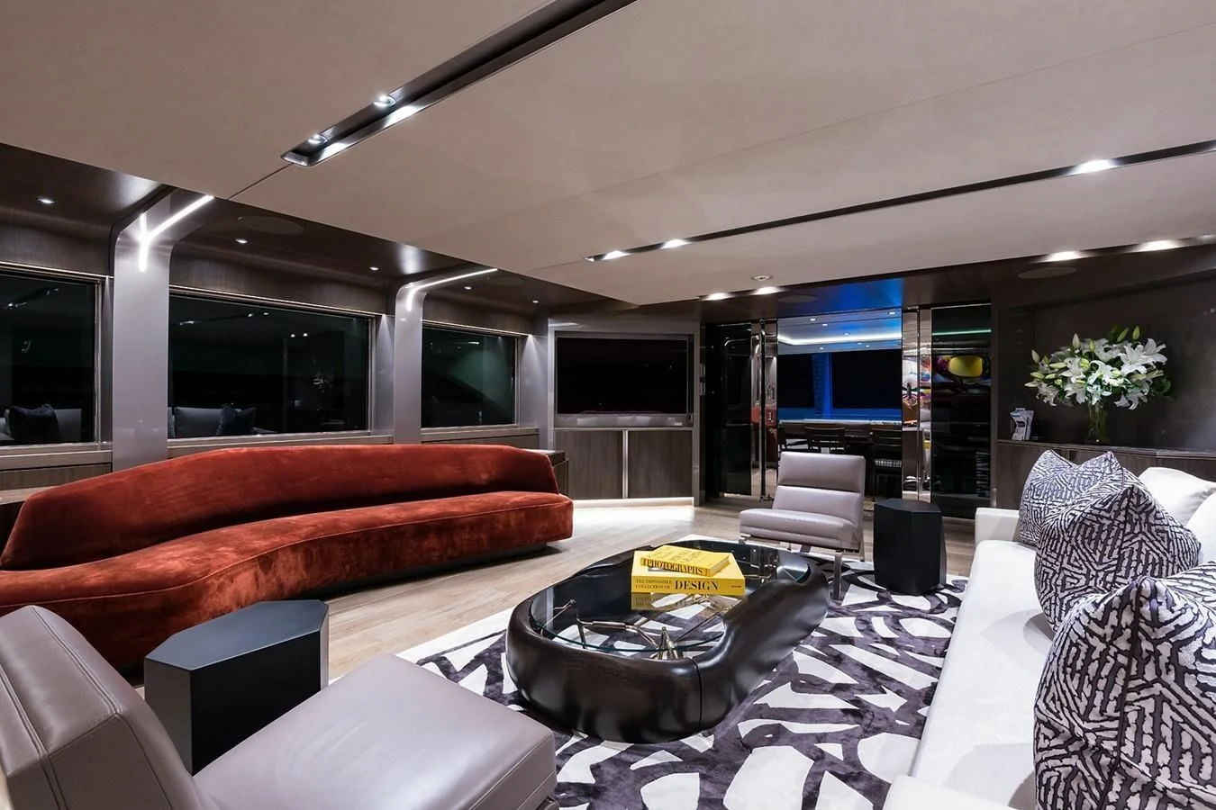 a modern living room with a large glass coffee table aboard SERENITY Yacht for Sale