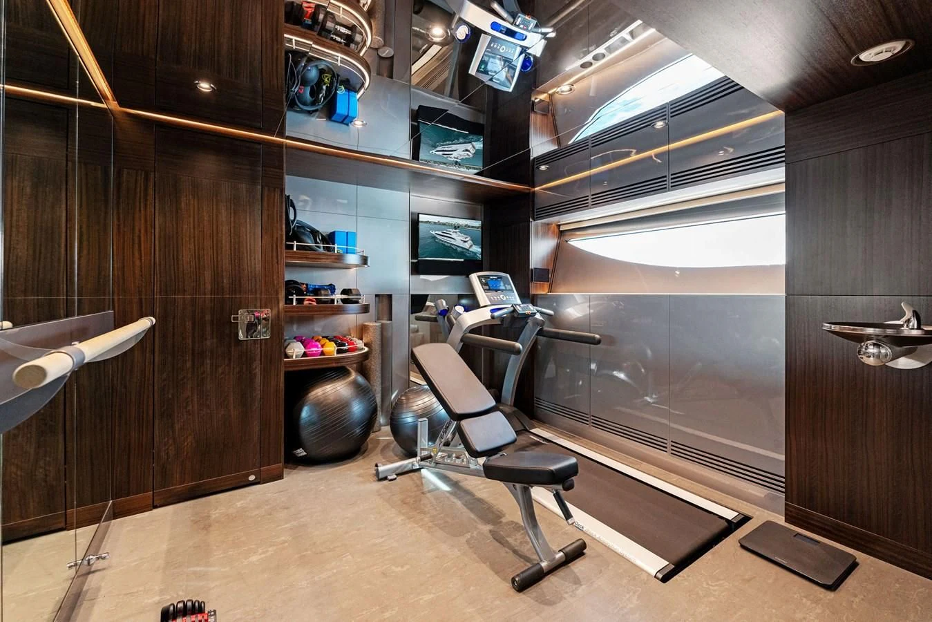 a room with a wood wall and a desk with chairs and a shelf with computer screens aboard SERENITY Yacht for Sale