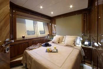 a bed with a white sheet and pillows in a room with wood walls aboard DRAGON Yacht for Sale