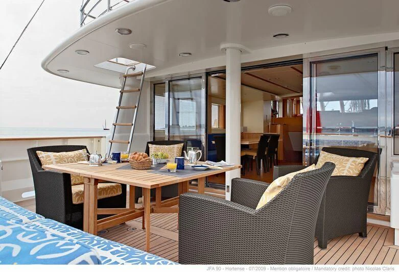 a dining table and chairs in a room with a ladder aboard HORTENSE Yacht for Sale