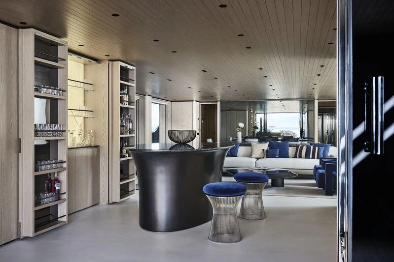 a room with a large glass coffee table and a large shelving unit aboard VIRTUOSITY Yacht for Sale