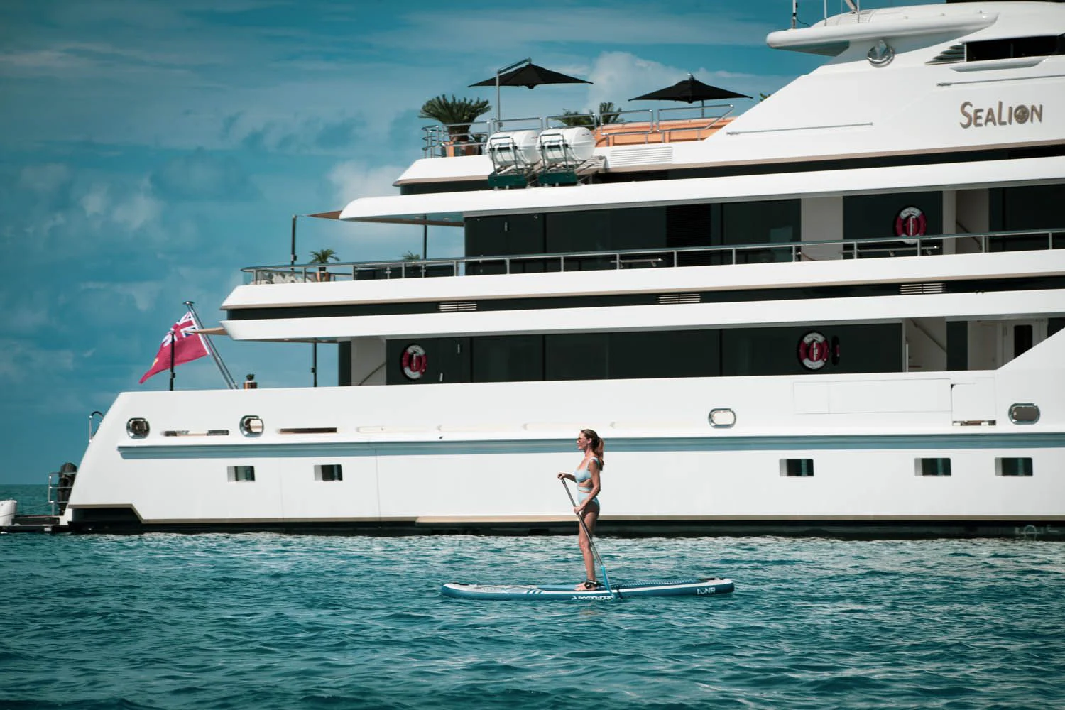 a man on a surfboard in front of a large cruise ship aboard SEALION Yacht for Sale