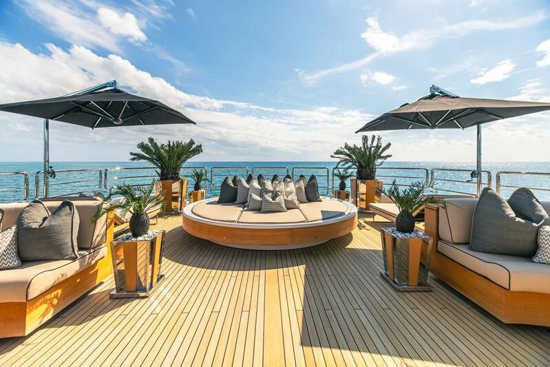 a deck with a table and chairs and umbrellas on it aboard SEALION Yacht for Sale
