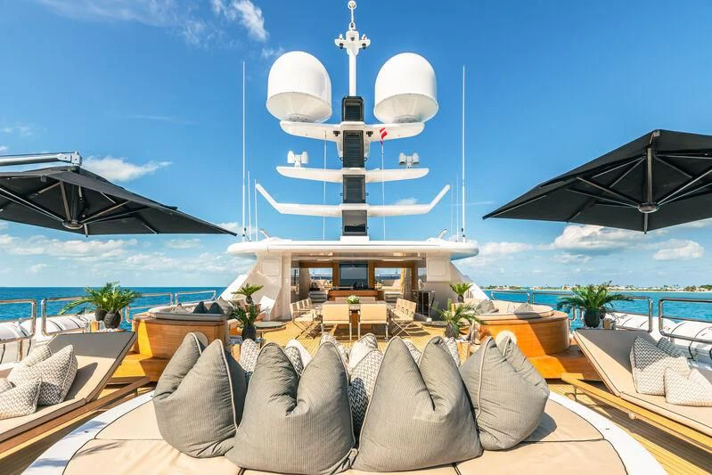 a deck with chairs and a large ship in the background aboard SEALION Yacht for Sale