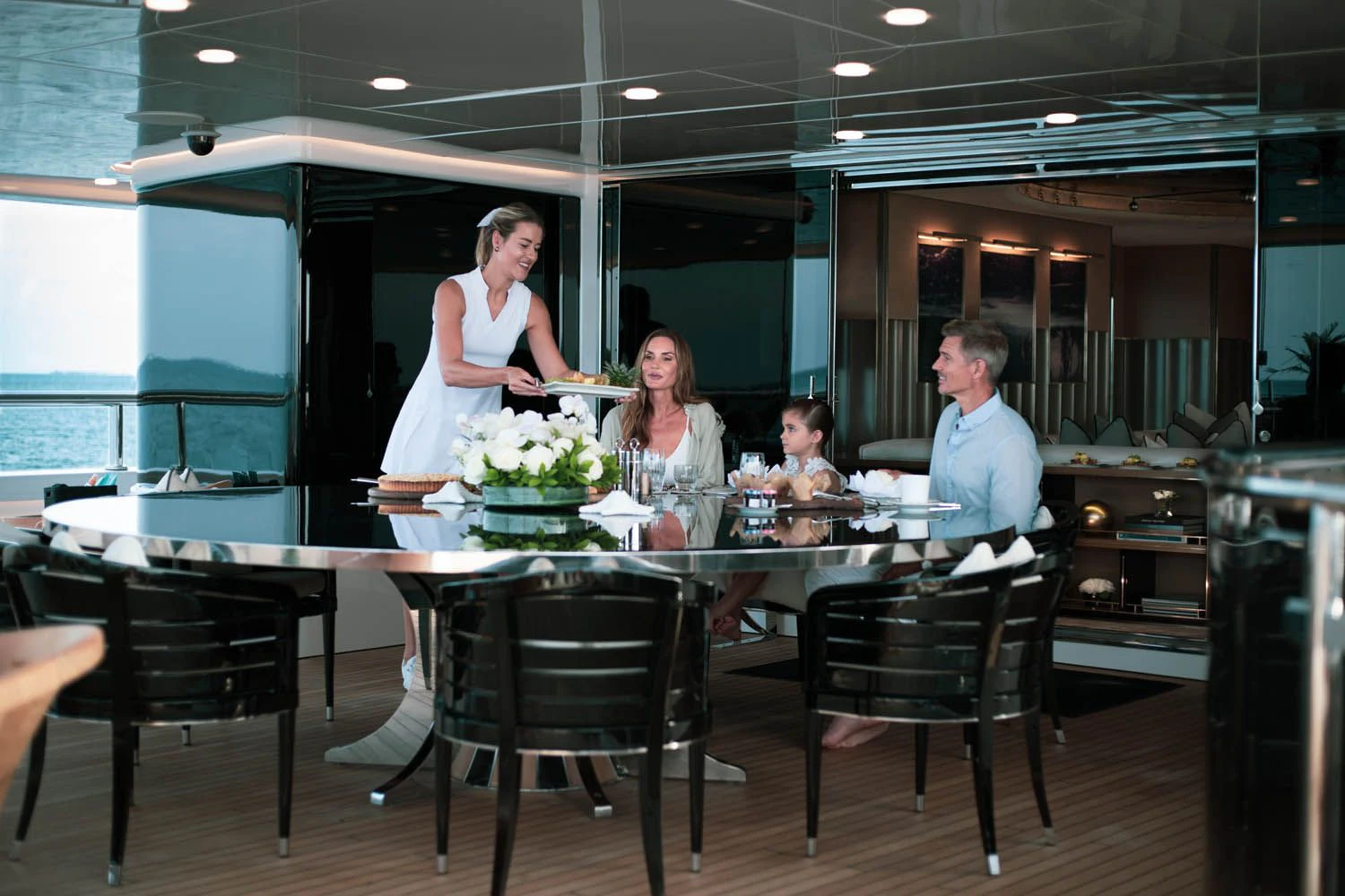 a man and woman standing at a table with a man and woman sitting at it aboard SEALION Yacht for Sale