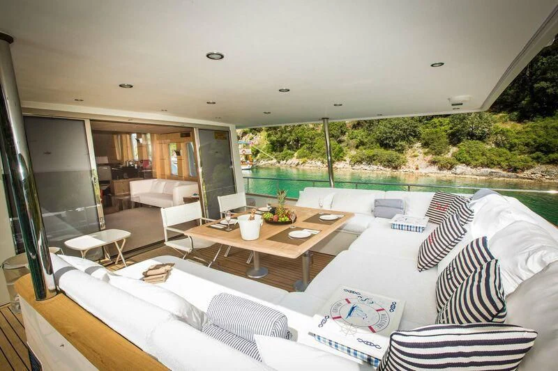 a room with a large bed and a table with chairs aboard DALI Yacht for Sale