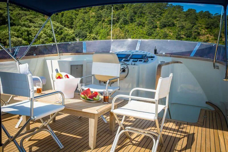 a deck with a table and chairs on it aboard DALI Yacht for Sale