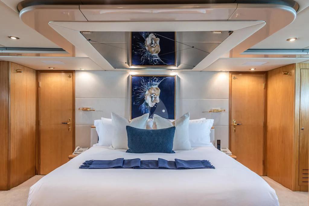 a bed with a white bed spread and a wood cabinet aboard SURINA Yacht for Sale