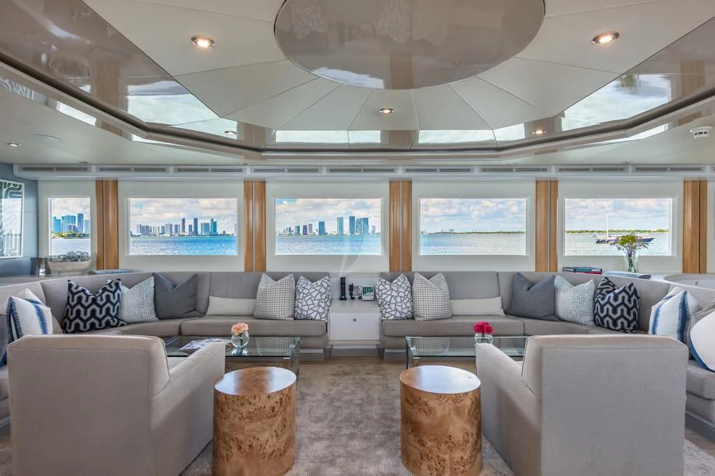 a living room with a large sectional sofa and a large window aboard SURINA Yacht for Sale