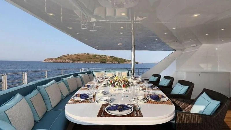 a large room with a table and chairs and a large body of water aboard EGO Yacht for Sale