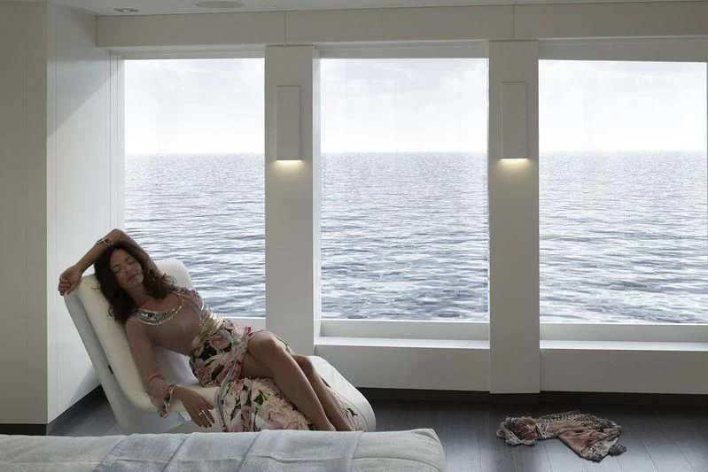 a person sitting on a bed aboard HOME Yacht for Charter