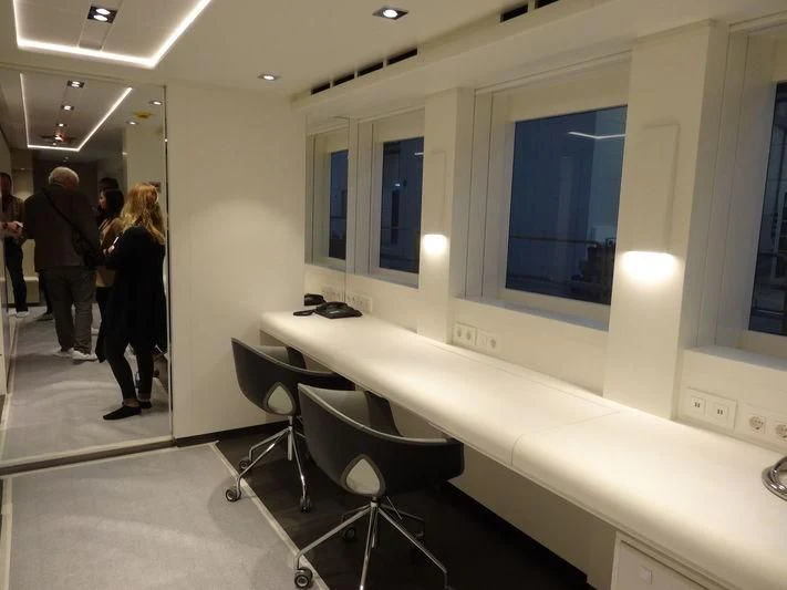 a room with a white table and chairs and a white rectangular object with a blue screen aboard HOME Yacht for Charter