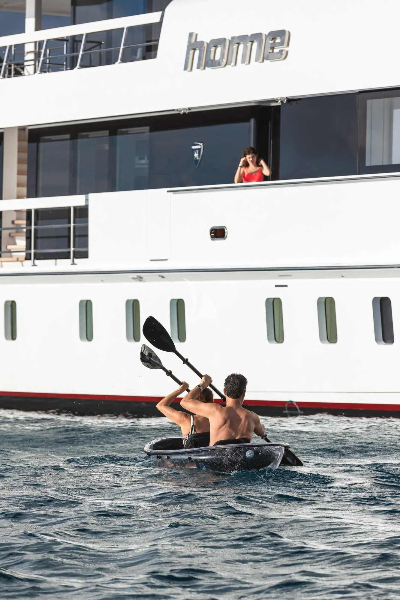 a man and woman in a kayak in front of a white boat aboard HOME Yacht for Charter