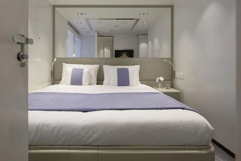 a bed with a blue comforter aboard HOME Yacht for Charter