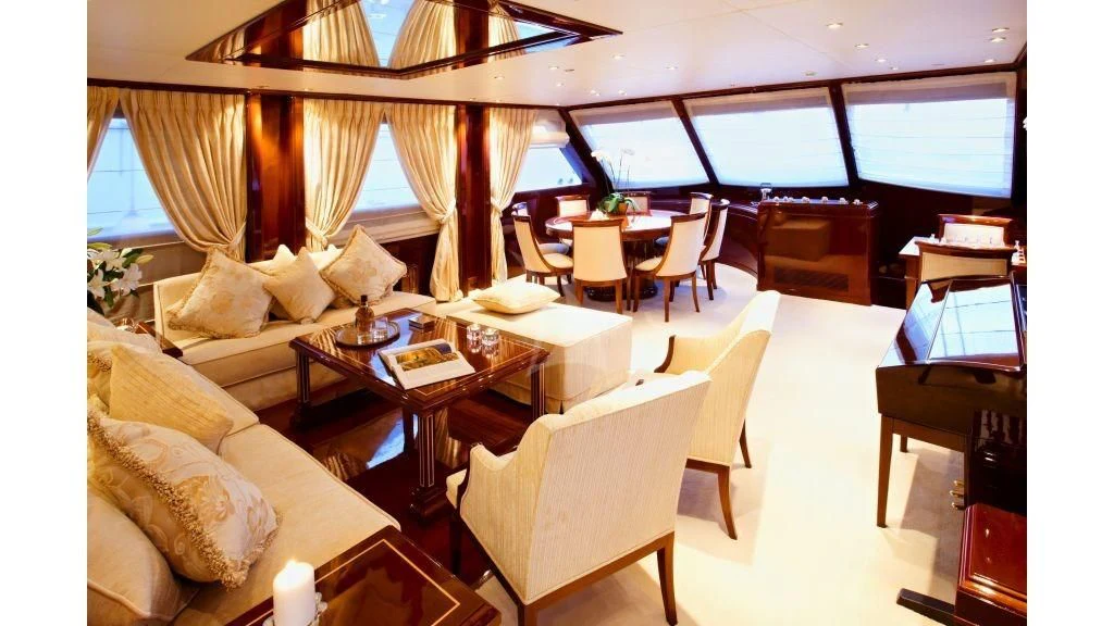 a room with a couch and a table with chairs and a window aboard IRAKLIS L Yacht for Charter