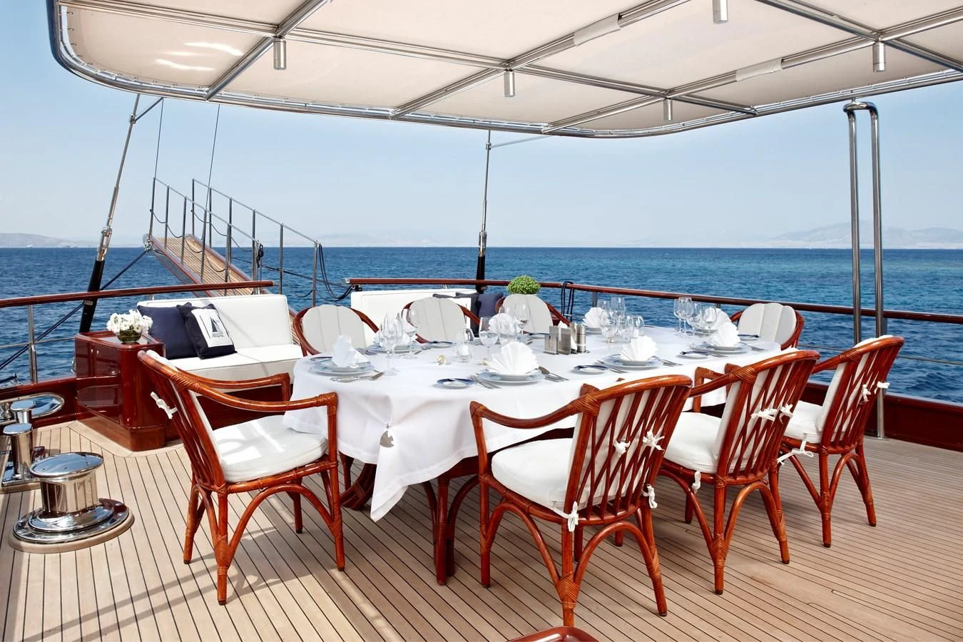 a table set for a dinner on a deck overlooking the ocean aboard IRAKLIS L Yacht for Charter