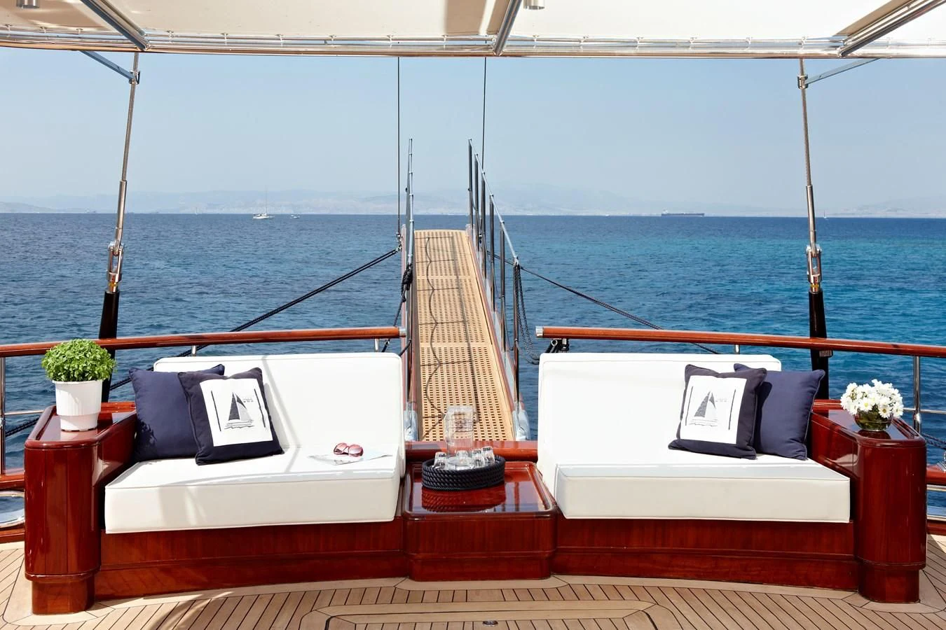 a deck with a view of the ocean and a couple of white beds aboard IRAKLIS L Yacht for Charter