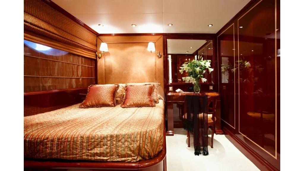 a bed with a table and a chair in a room aboard IRAKLIS L Yacht for Charter