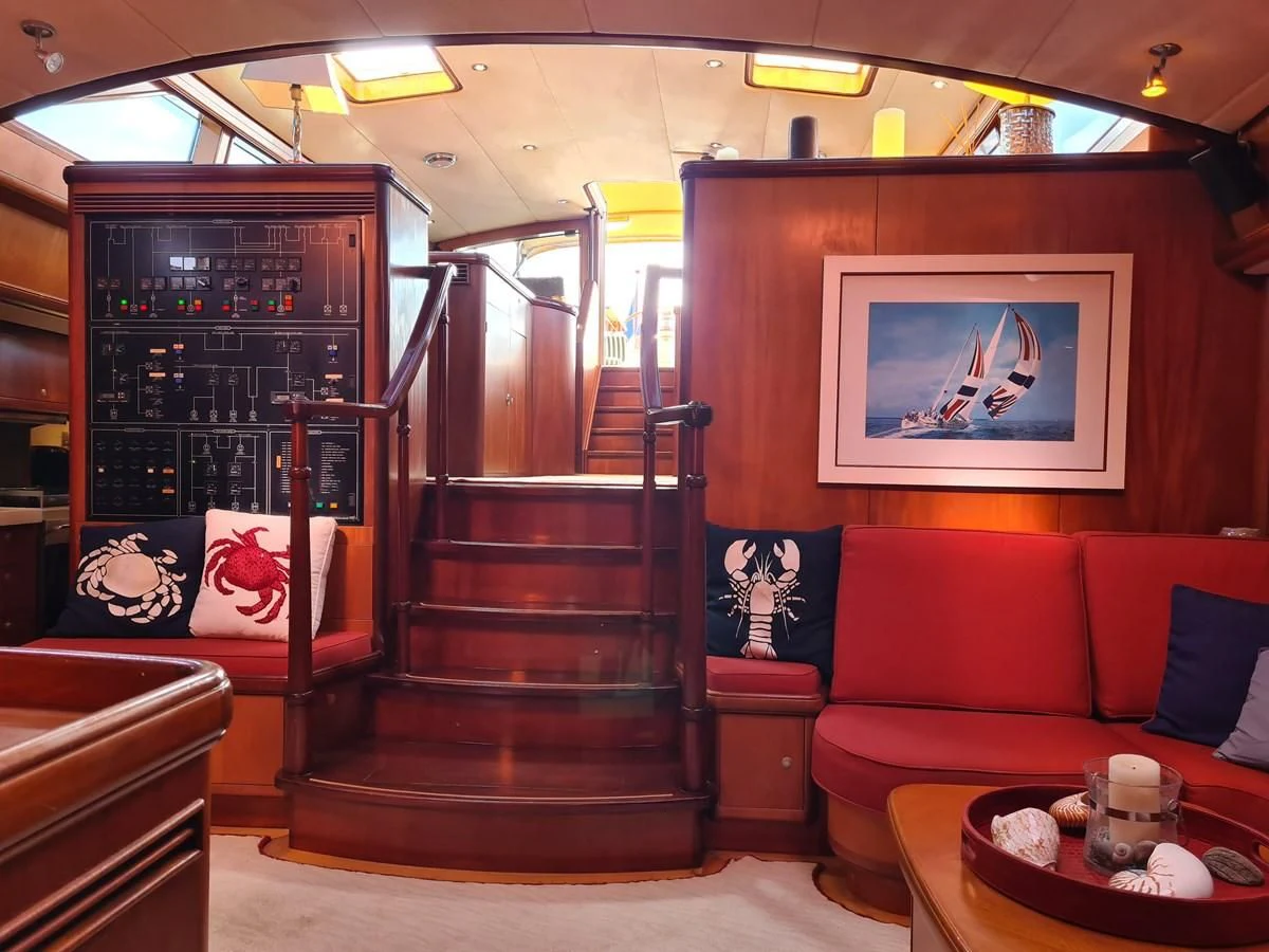 a living room with a red couch and a wood staircase aboard WHIRLWIND Yacht for Sale