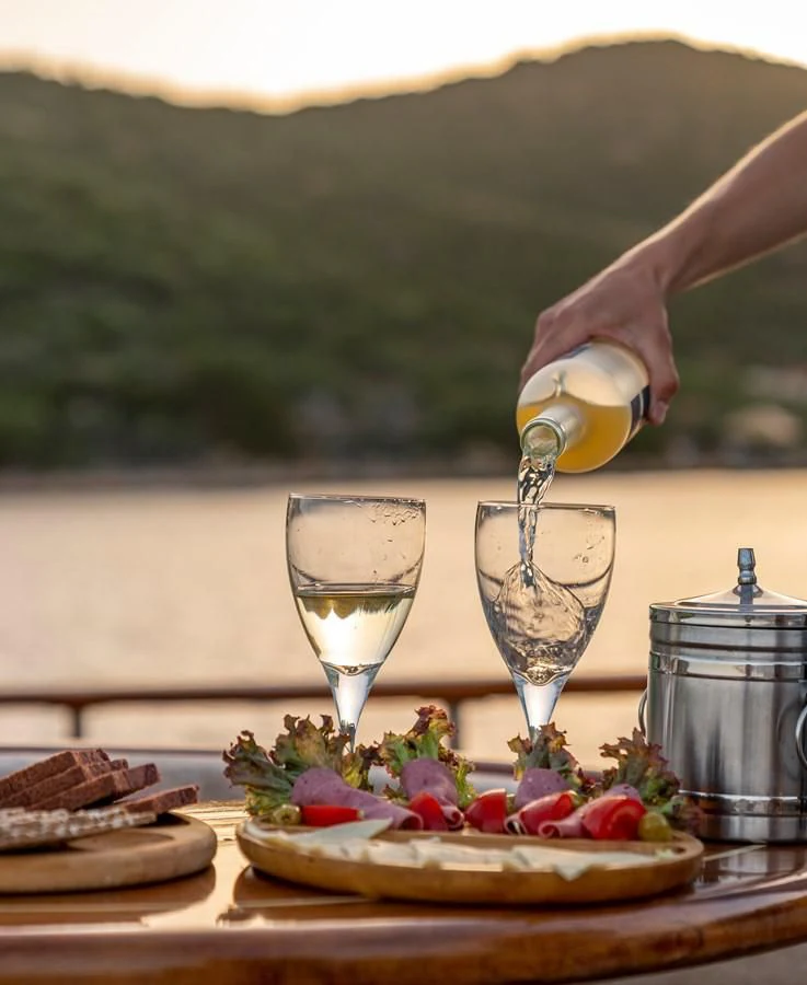 a person pouring wine into a glass aboard L'ORIENT Yacht for Sale