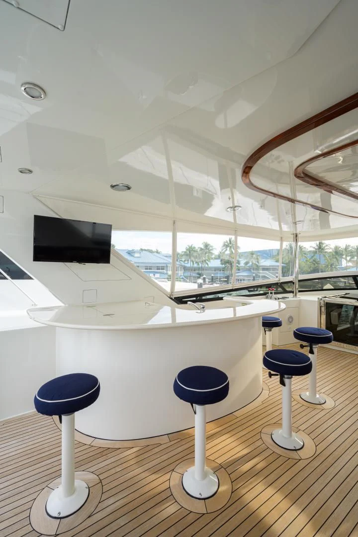 a room with a large window and a table with stools aboard SUPERSTAR Yacht for Charter